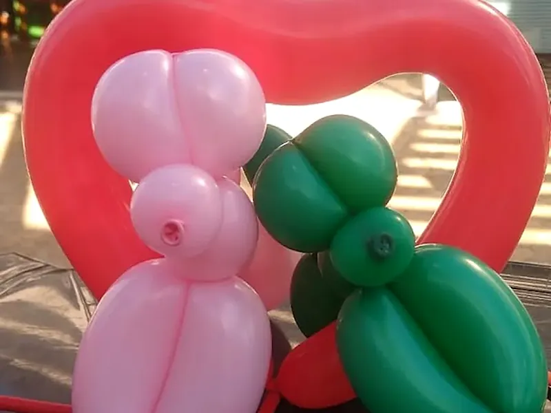 Escultura de balão em forma de bichinho sobre uma flor de bexiga
