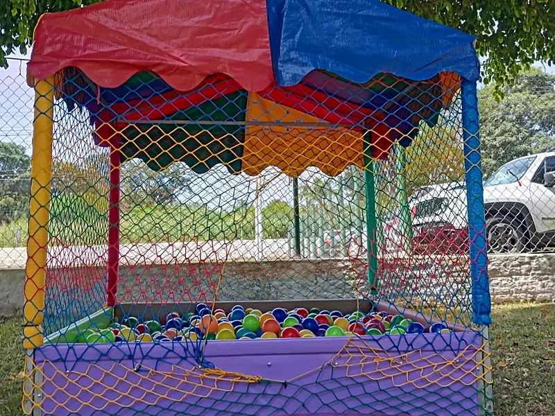 Piscina de bolinhas com toldo vermelho e azul e rede de proteção